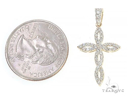 14K yellow gold twisted cross pendant with diamond accents next to a quarter for size comparison