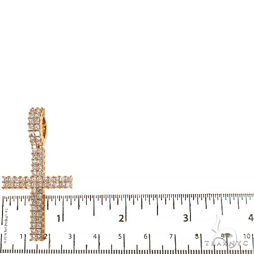 Yellow gold cross pendant with two rows of princess cut diamonds, next to ruler for size