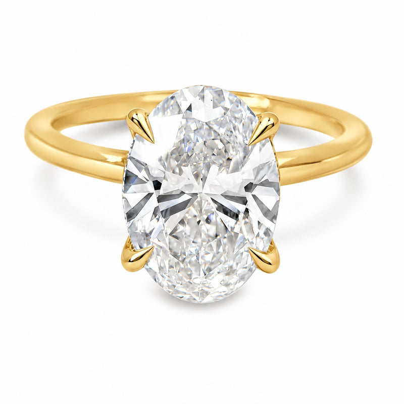 18K yellow gold engagement ring featuring a 5 carat oval lab grown diamond, four claw prongs, a delicate hidden halo, and a polished solitaire band