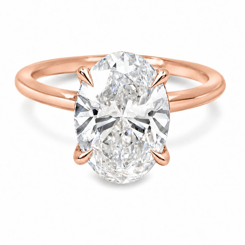 18K rose gold engagement ring featuring a 5 carat oval lab grown diamond, four claw prongs, a delicate hidden halo, and a polished solitaire band