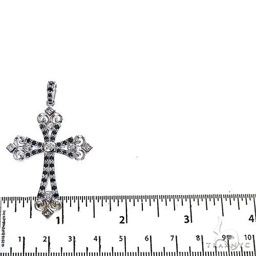 White gold cross pendant with black diamonds and intricate detailing, shown next to ruler for size