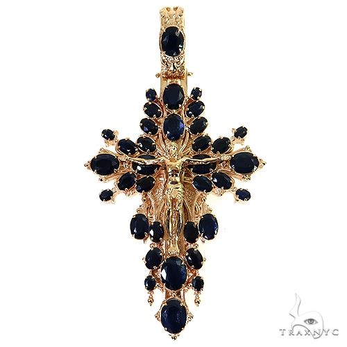 Yellow gold cross pendant with sapphire gemstones and detailed Jesus figure centerpiece