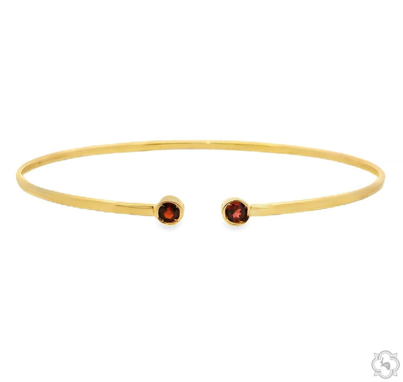 polished gold open bangle bracelet with two red gemstones at open terminals, front angle