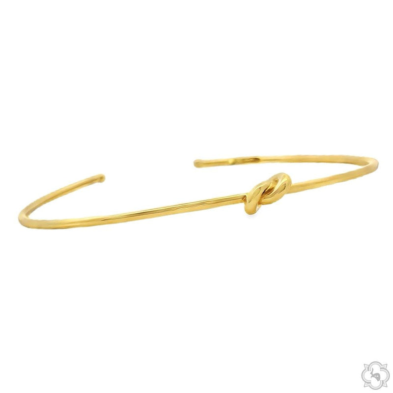 Yellow gold-tone open bangle bracelet with a central knot detail for women