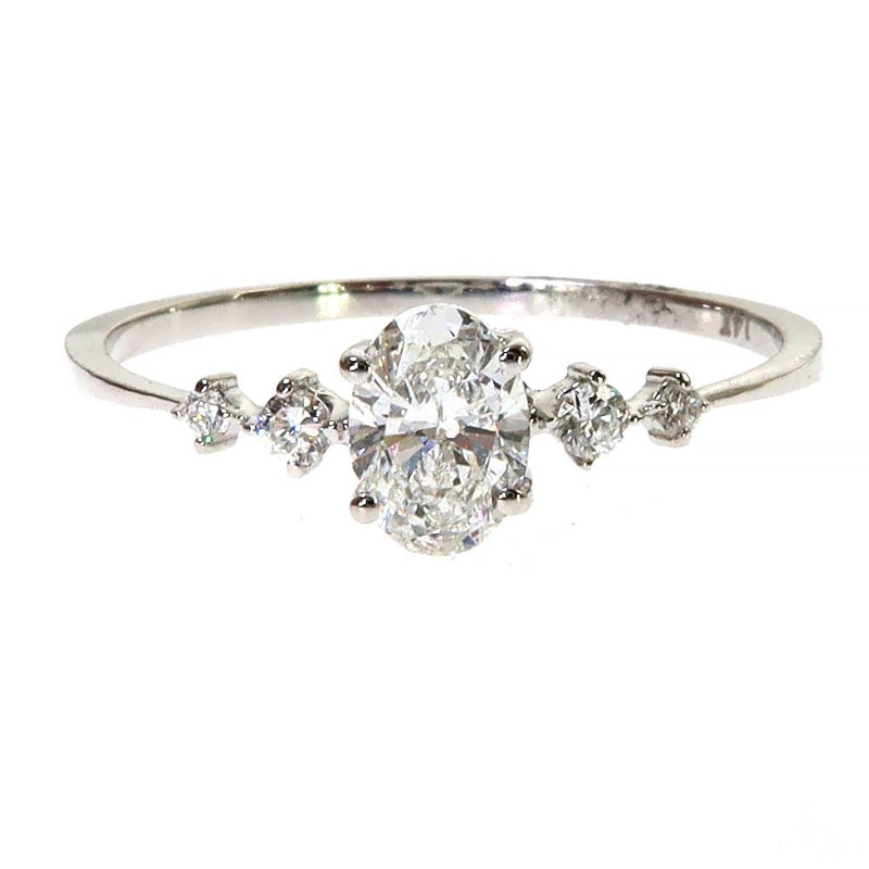 White gold oval diamond ring with six surrounding smaller diamonds on slender band