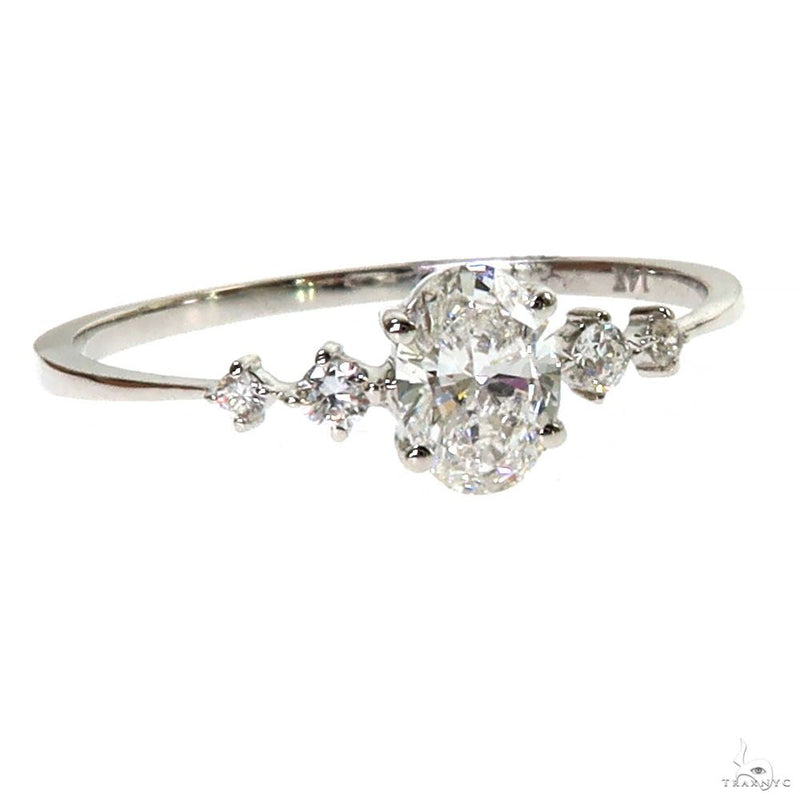White gold oval diamond ring with six surrounding smaller diamonds on slender band