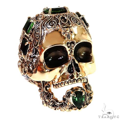 Yellow gold skull ring with black and green gemstone accents and intricate filigree detailing
