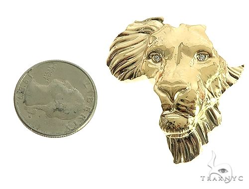 Small yellow gold lion face pendant with detailed mane next to a quarter for size reference