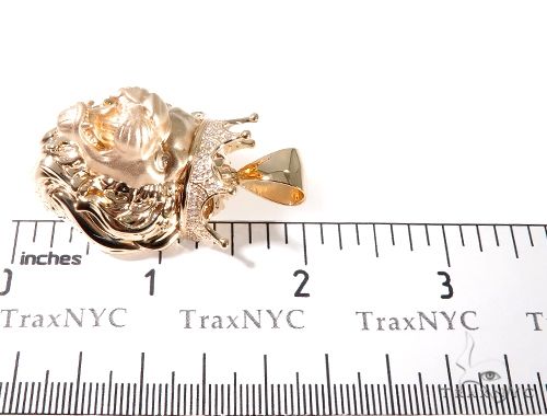 Small rose gold lion head pendant with diamond accents resting on ruler background