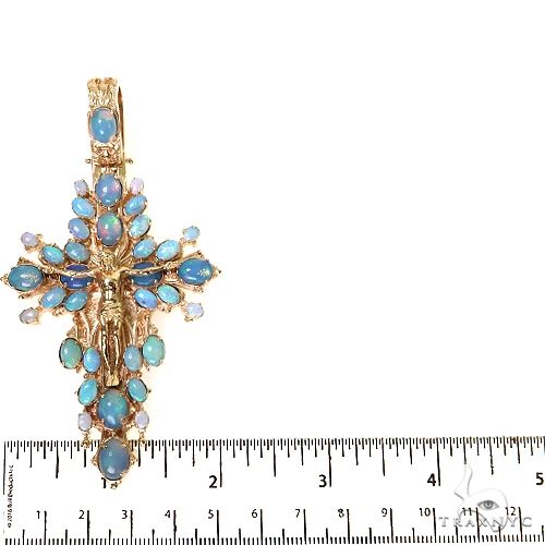 Yellow gold cross pendant with blue opal gemstones and detailed Jesus figure centerpiece