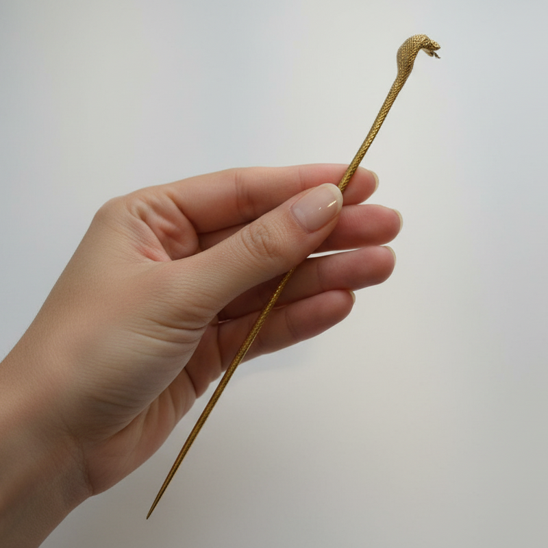 24K gold hairpin with detailed cobra head design held in hand