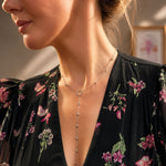 Sterling silver lariat necklace with delicate chain and small bead accents, worn with floral dress.