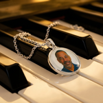 925 silver round pendant with photo on silver chain necklace resting on piano keys.