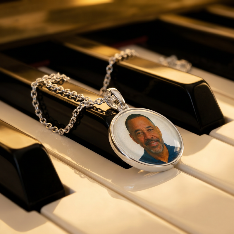 925 silver round pendant with photo on silver chain necklace resting on piano keys.