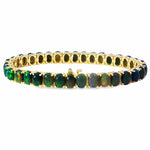 Gold tennis bracelet with oval black opal gemstones in a continuous setting.