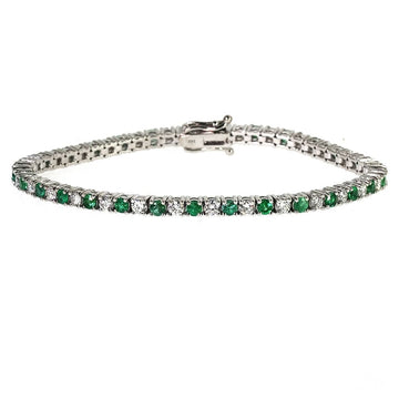 White gold tennis bracelet with alternating emerald and diamond gemstones.