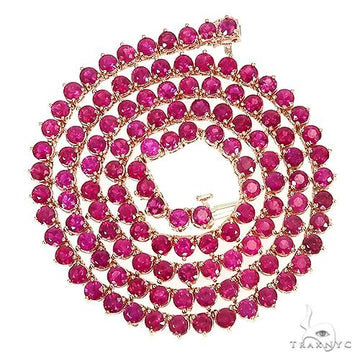 14K gold tennis chain with round ruby gemstones in 3-prong settings, coiled design.