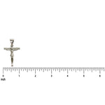 Small silver crucifix pendant with detailed Jesus figure on inch ruler background.