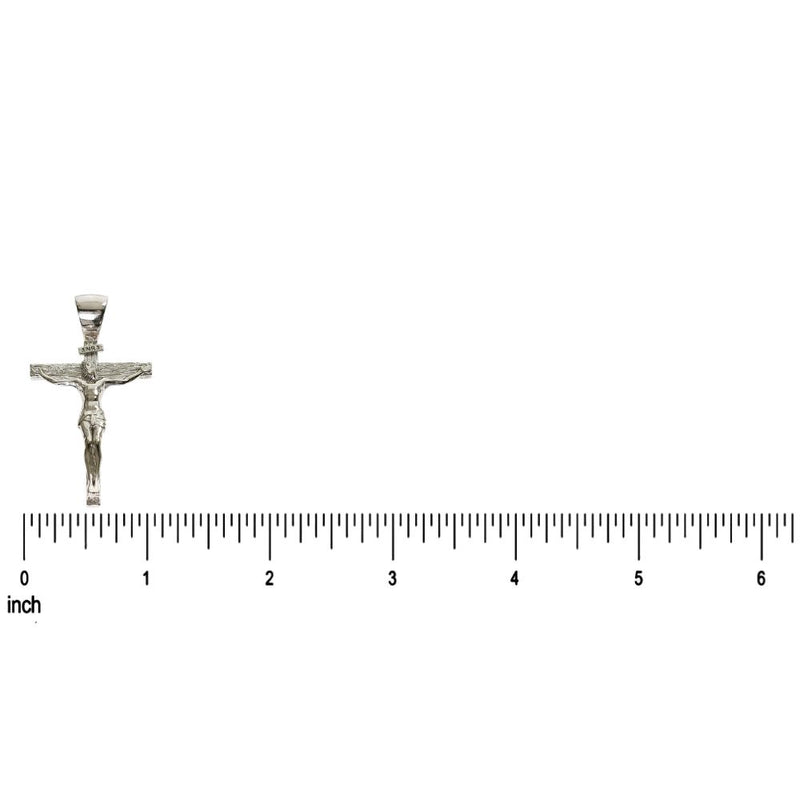 Small silver crucifix pendant with detailed Jesus figure on inch ruler background.