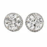 Round white gold diamond stud earrings with halo design and brilliant cut stones.