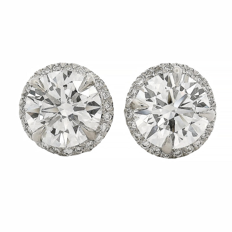 Round white gold diamond stud earrings with halo design and brilliant cut stones.