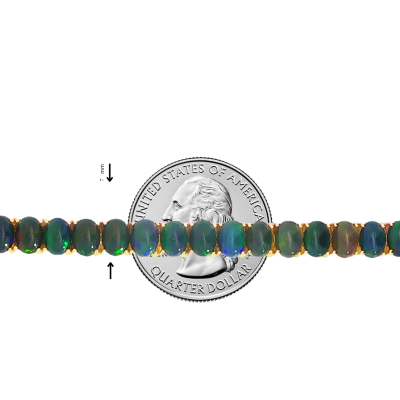 Gold tennis bracelet with oval black opal gemstones, shown alongside a U.S. quarter for size comparison.
