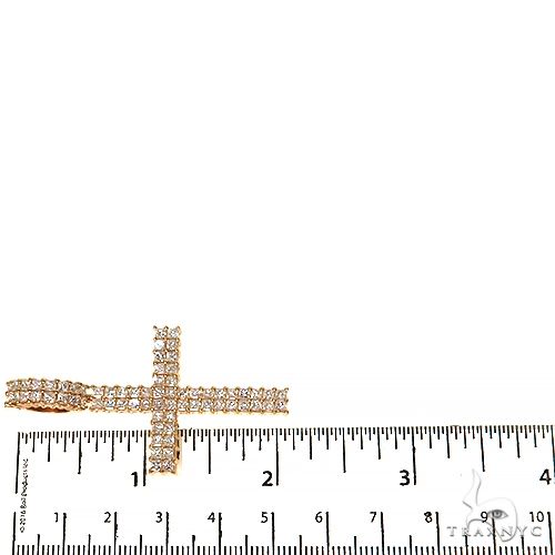 Yellow gold cross pendant with two rows of princess cut diamonds, shown on ruler for size