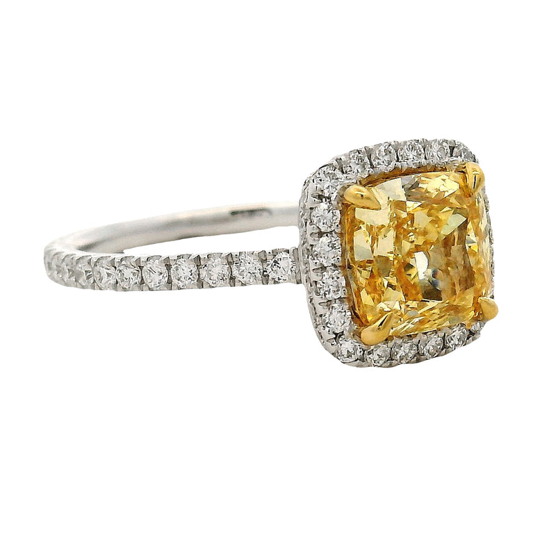 Cushion-cut yellow diamond ring with halo of white diamonds on a white gold band.