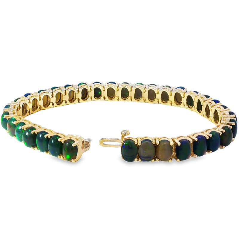 Gold tennis bracelet with oval galaxy black opals in a continuous setting.