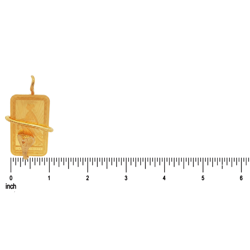 Gold pendant with a ruler for scale on a white background