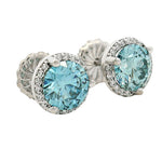 Round blue gemstone stud earrings with diamond halo in white gold setting.