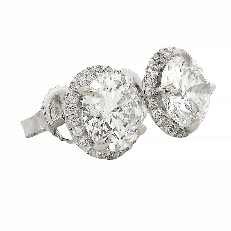 Round white gold diamond stud earrings with halo design and brilliant cut stones.