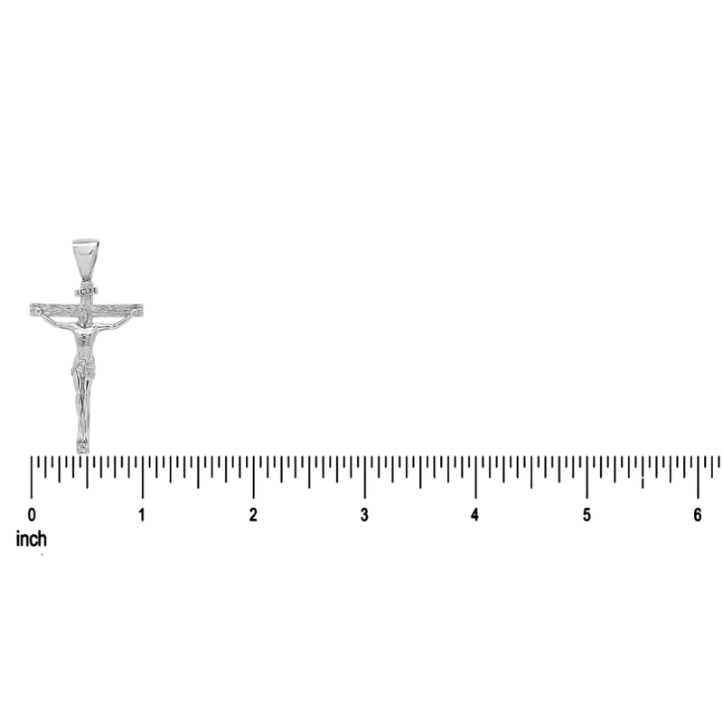 Silver Jesus crucifix pendant with detailed figure and Cuban curb chain on ruler background.