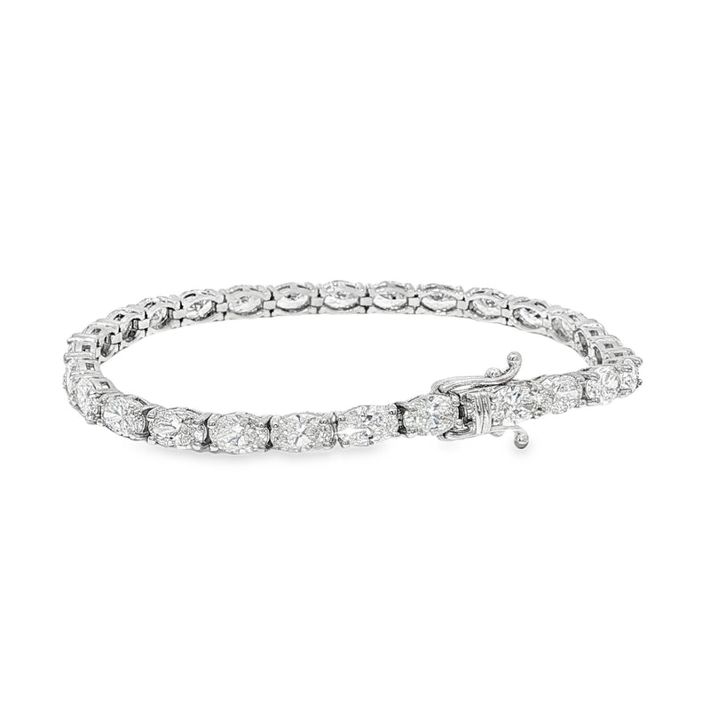 White gold tennis bracelet with oval-cut diamonds in a linked setting.