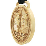 Gold-tone circular medal pendant with embossed man and robot faces and "MAN vs ROBOT" text.