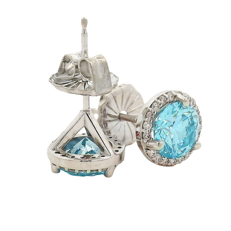 Round blue gemstone stud earrings with diamond halo in white gold setting.