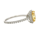 Cushion-cut yellow diamond ring with halo of white diamonds on a white gold band.