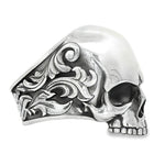 Silver skull ring with antique finish and ornate floral engravings on the band.