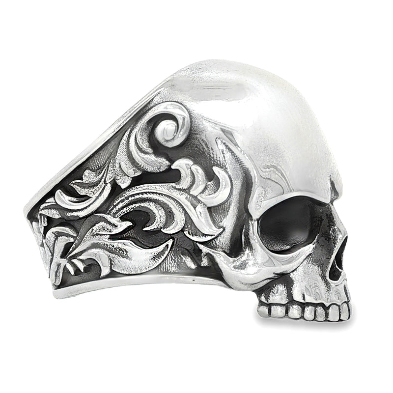 Silver skull ring with antique finish and ornate floral engravings on the band.