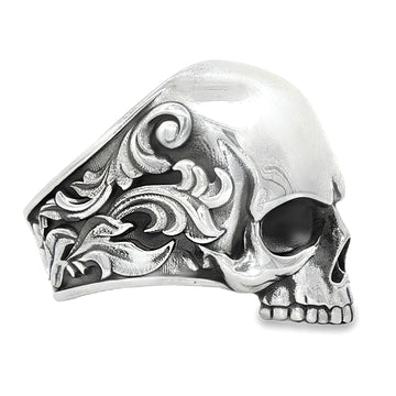 Silver skull ring with antique finish and ornate floral engravings on the band.