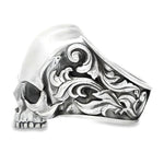 Silver skull ring with antique finish and ornate floral engravings on the band.
