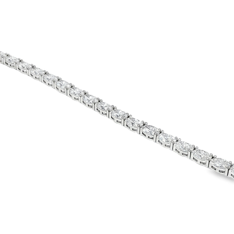 White gold tennis bracelet with oval-cut diamonds in a linked setting.