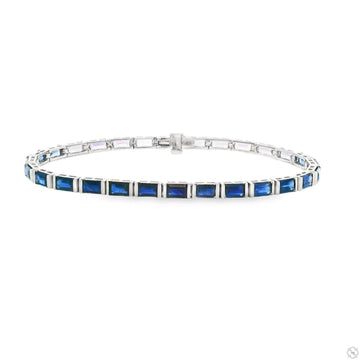 White gold tennis bracelet with baguette-cut ombre blue sapphire gemstones.