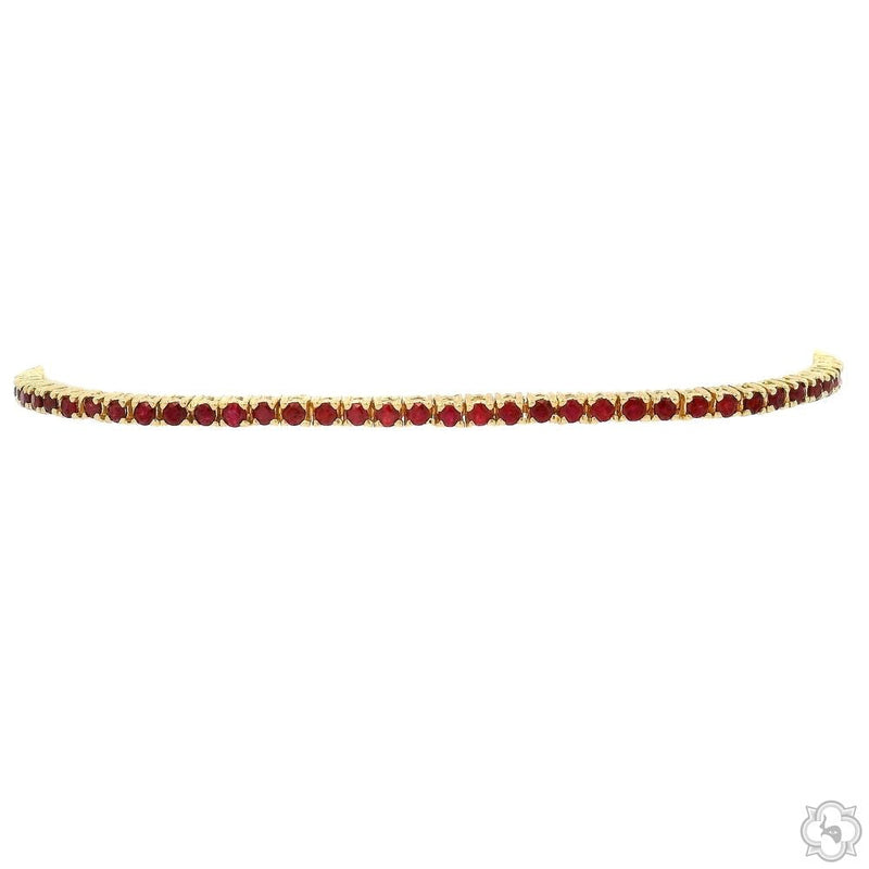 Yellow gold tennis bracelet with round ruby gemstones in a continuous line