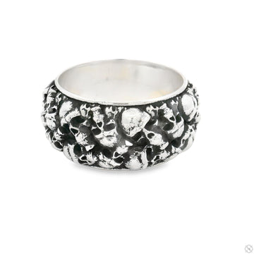 Silver band ring with detailed skull design on thick, textured surface.