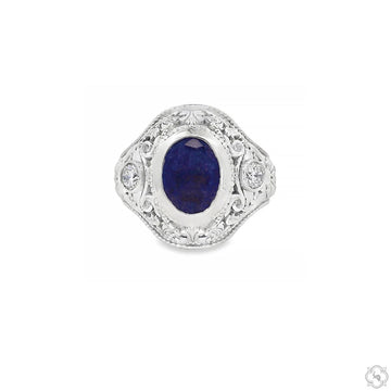 Silver filigree ring with deep blue oval sapphire center and intricate detailing.