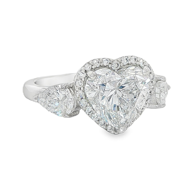 White gold engagement ring with heart-shaped center diamond and three-stone halo design.