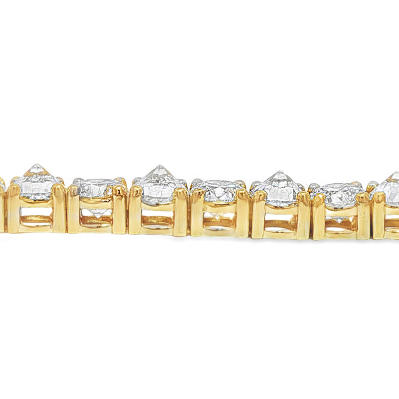 Yellow gold tennis bracelet with alternating upside-down round diamonds in secure clasp.