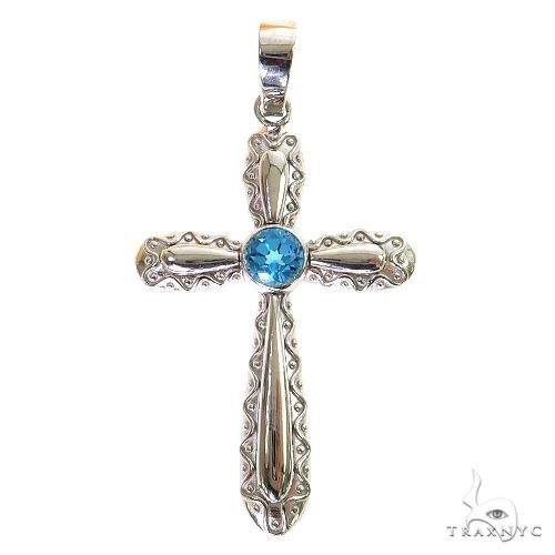 Silver cross pendant with intricate detailing and central round blue gemstone