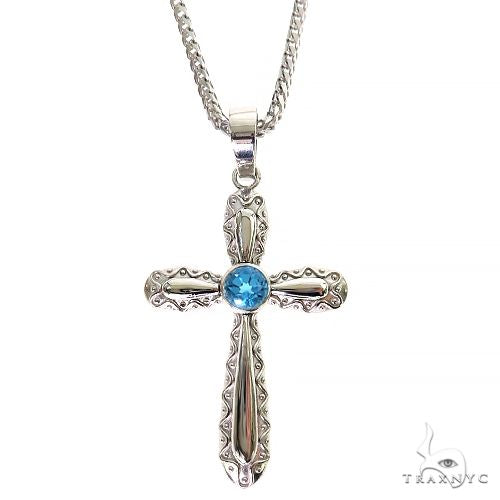 Silver cross pendant with intricate design and central round aqua blue gemstone on chain